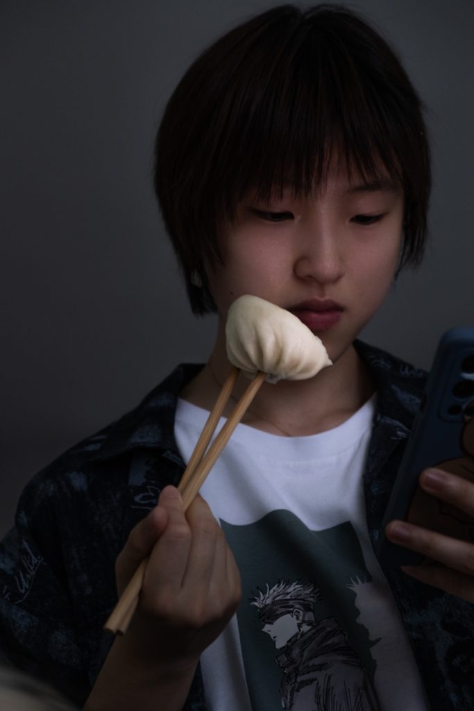 Zoe holding a steamed bun with chopsticks
